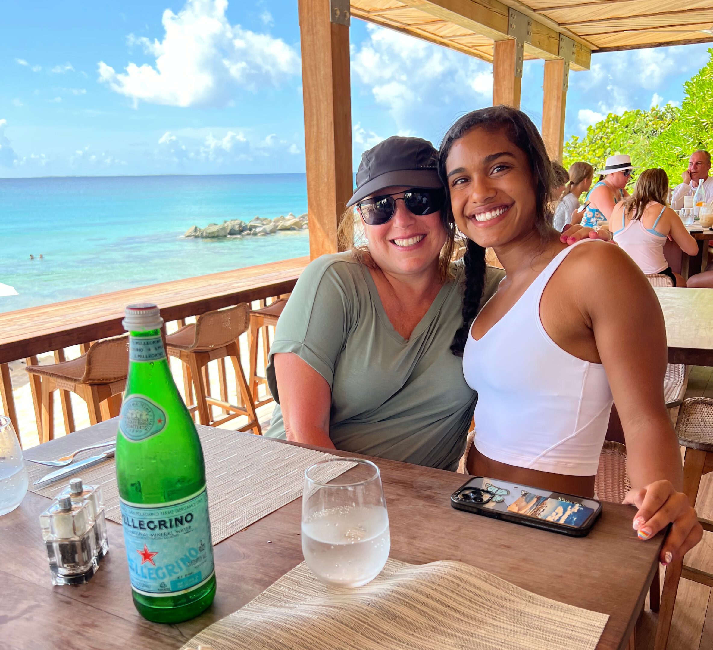 Two women sitting at a table with a bottle of wine.